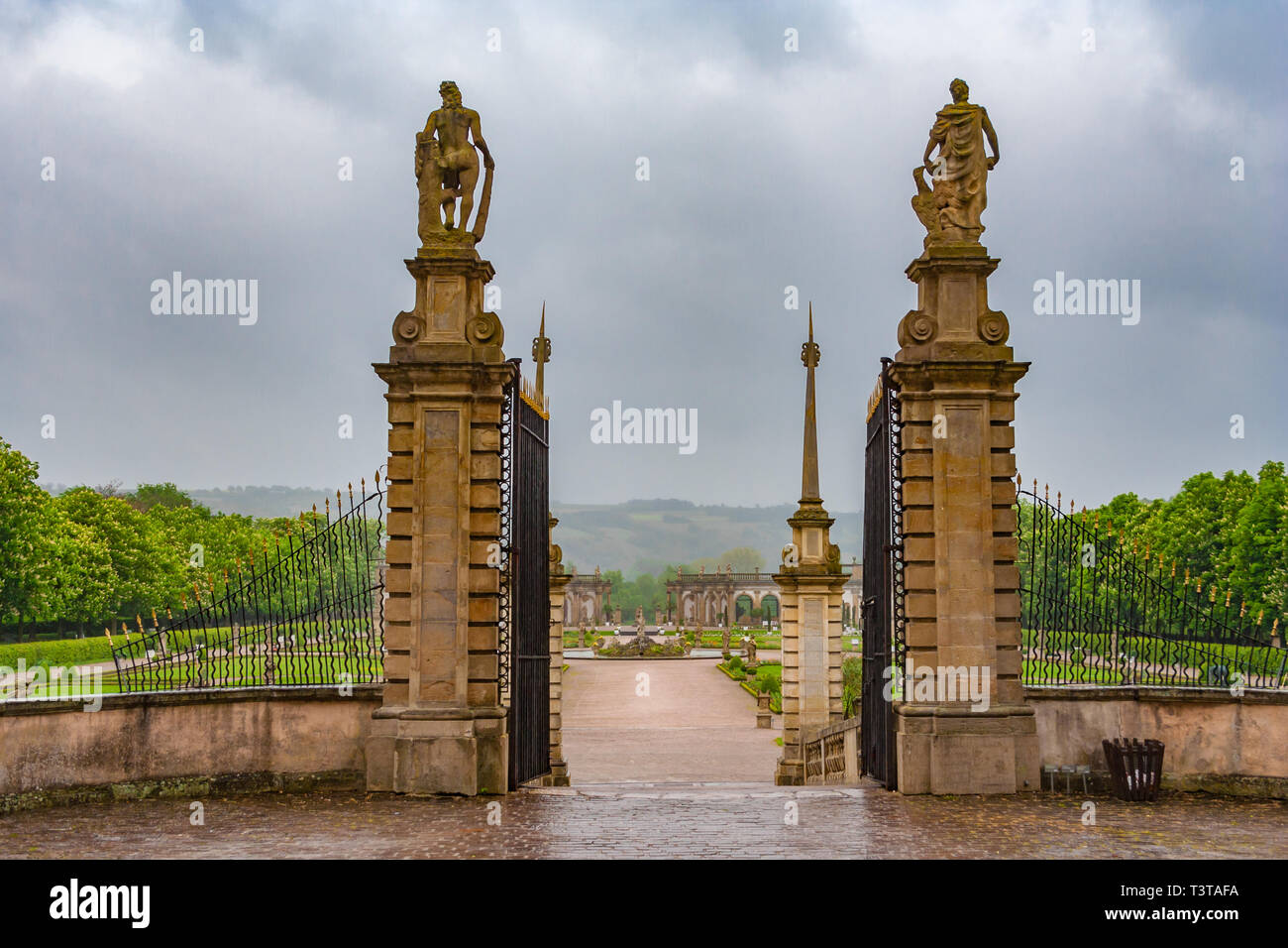 The grand open gated entrance with two statues to the Baroque garden from the famous Weikersheim Palace on a cloudy day in Germany. The walkway is... Stock Photo