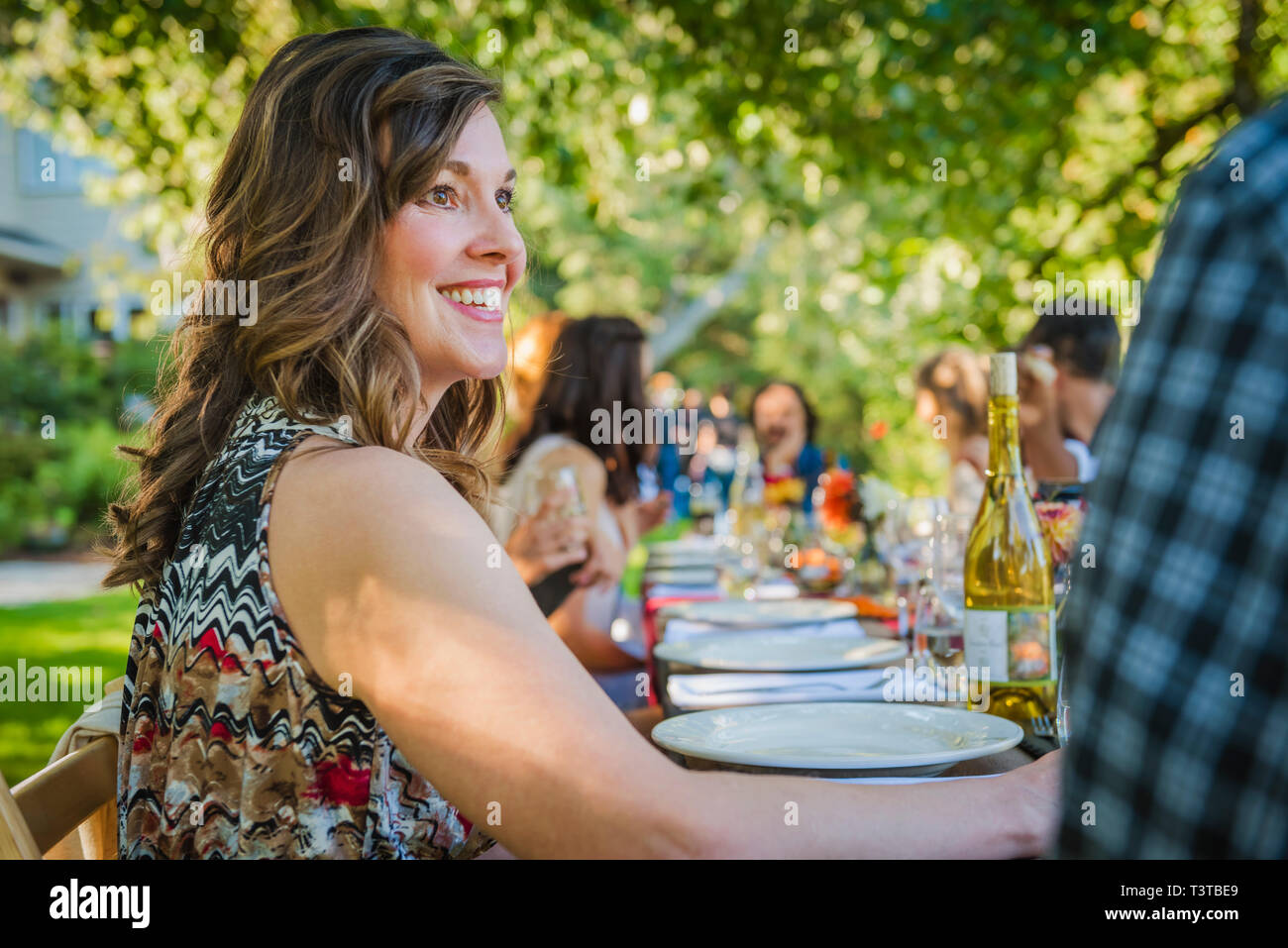Portrait of smiling Caucasian woman sitting at table at party outdoors Stock Photo