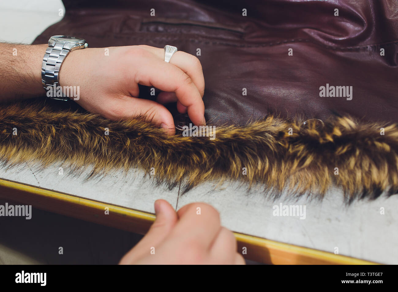 Professional tailor, designer repairing fur coat at atelier, studio