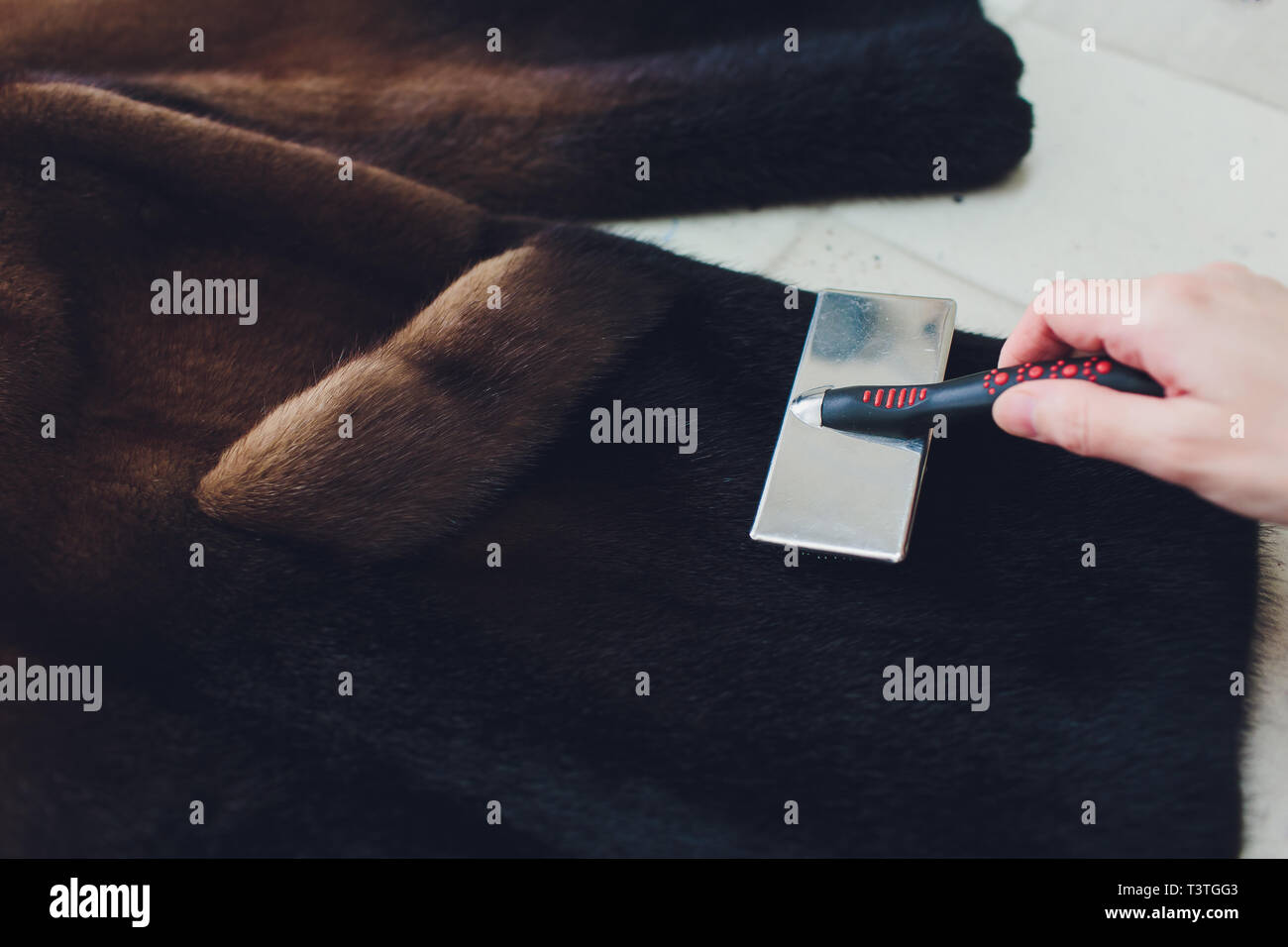 Dry cleaning business concept. Woman working with fur coat and brush