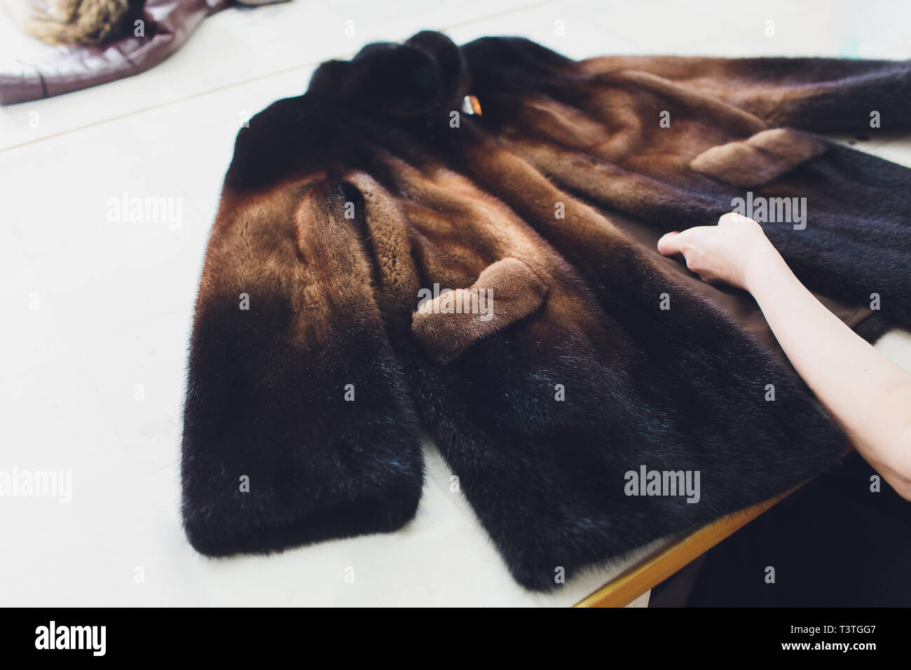 Dry cleaning business concept. Woman working with fur coat and brush