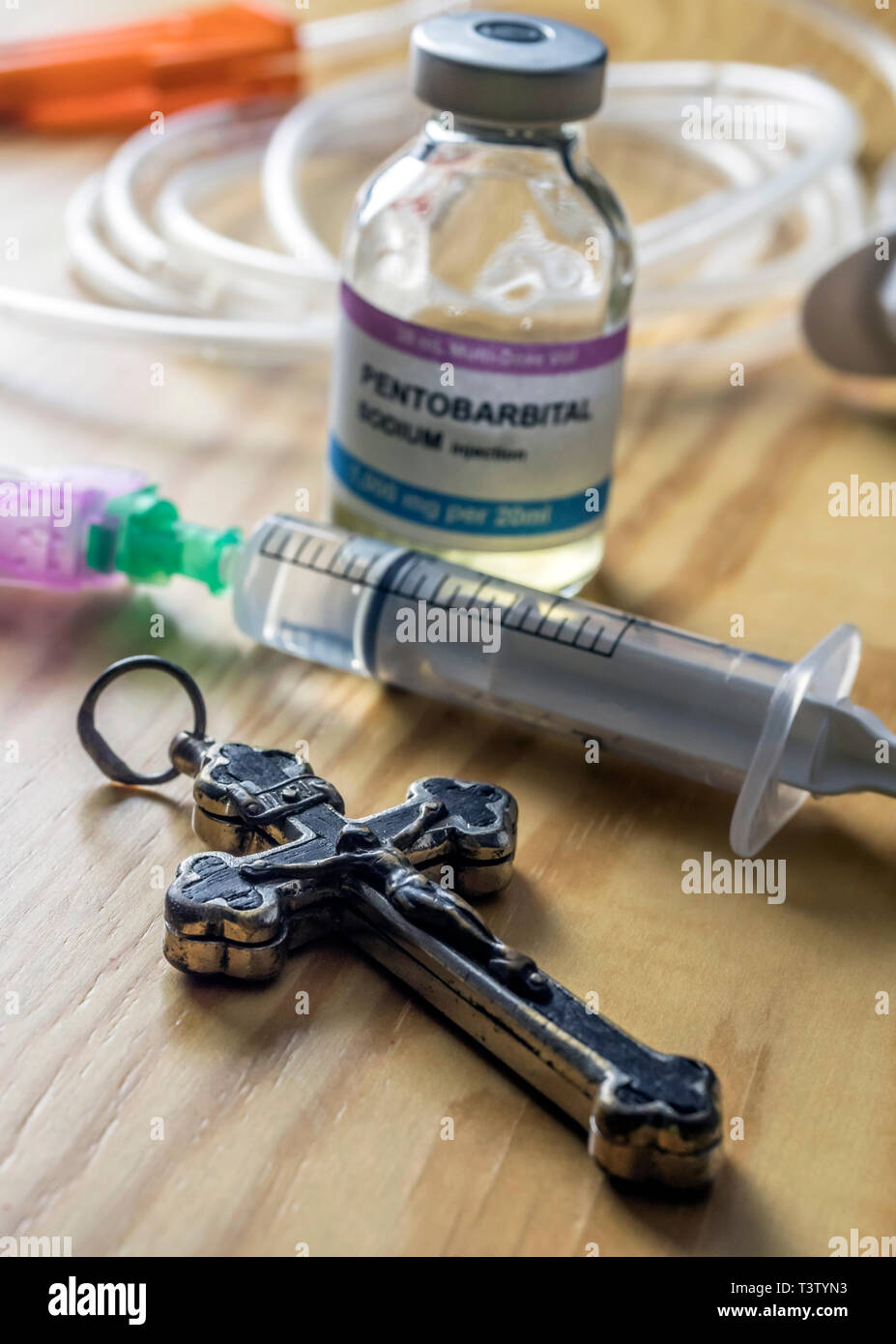 Vial with doses of pentobarbital next to a crucifix, Debate between life and death, religious belief in the face of euthanasia, conceptual image Stock Photo