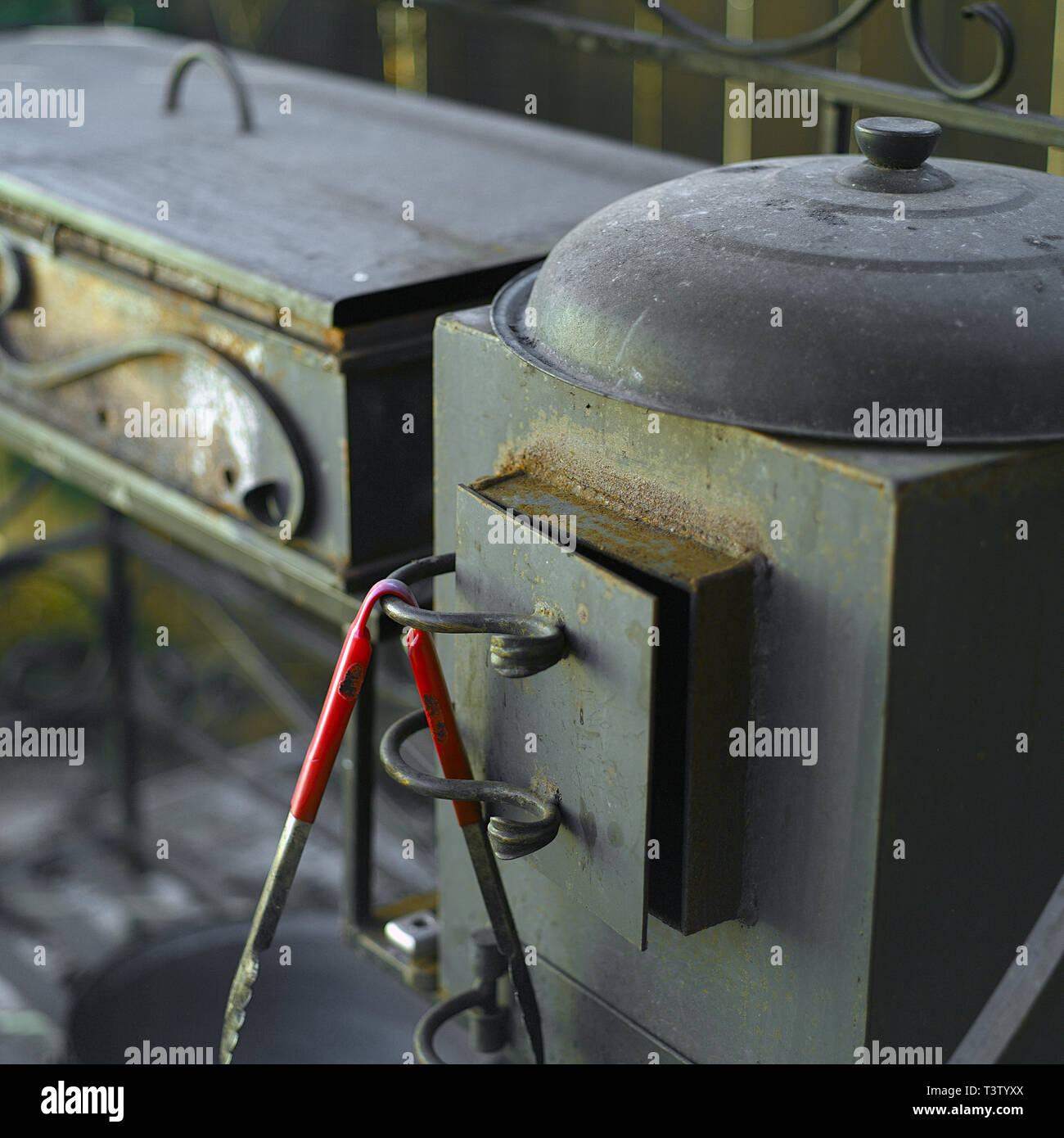 Tongs, cast iron stove and trolley for barbecue, outdoor closeup shot Stock Photo