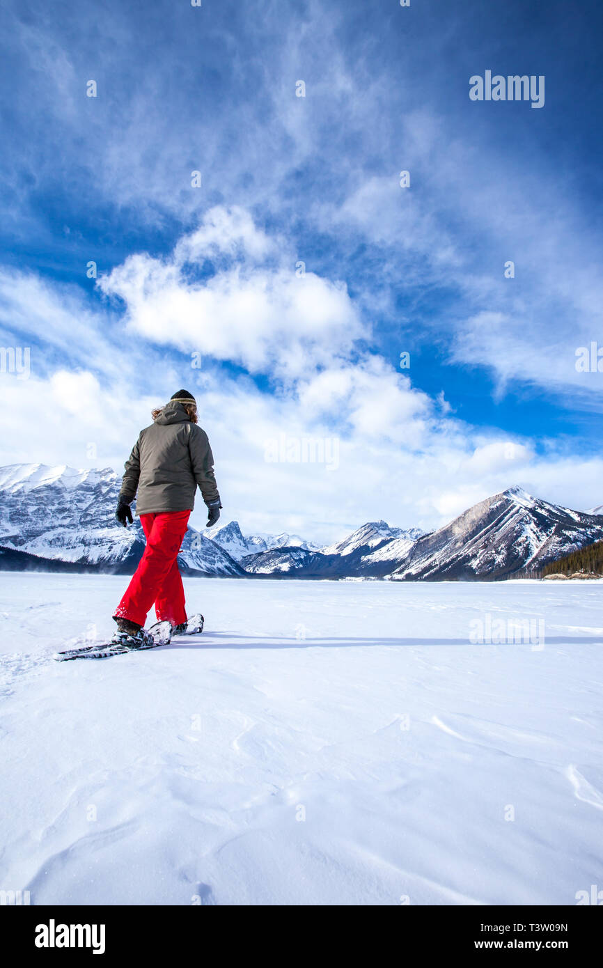 Young woman snowshoeing on a frozen lake in the Canadian Rocky Mountains, Kananaskis, Alberta, Canada Stock Photo