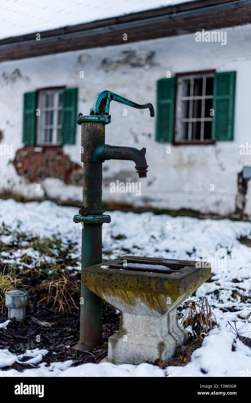 faucet in the snow in front of an old farmhouse Stock Photo