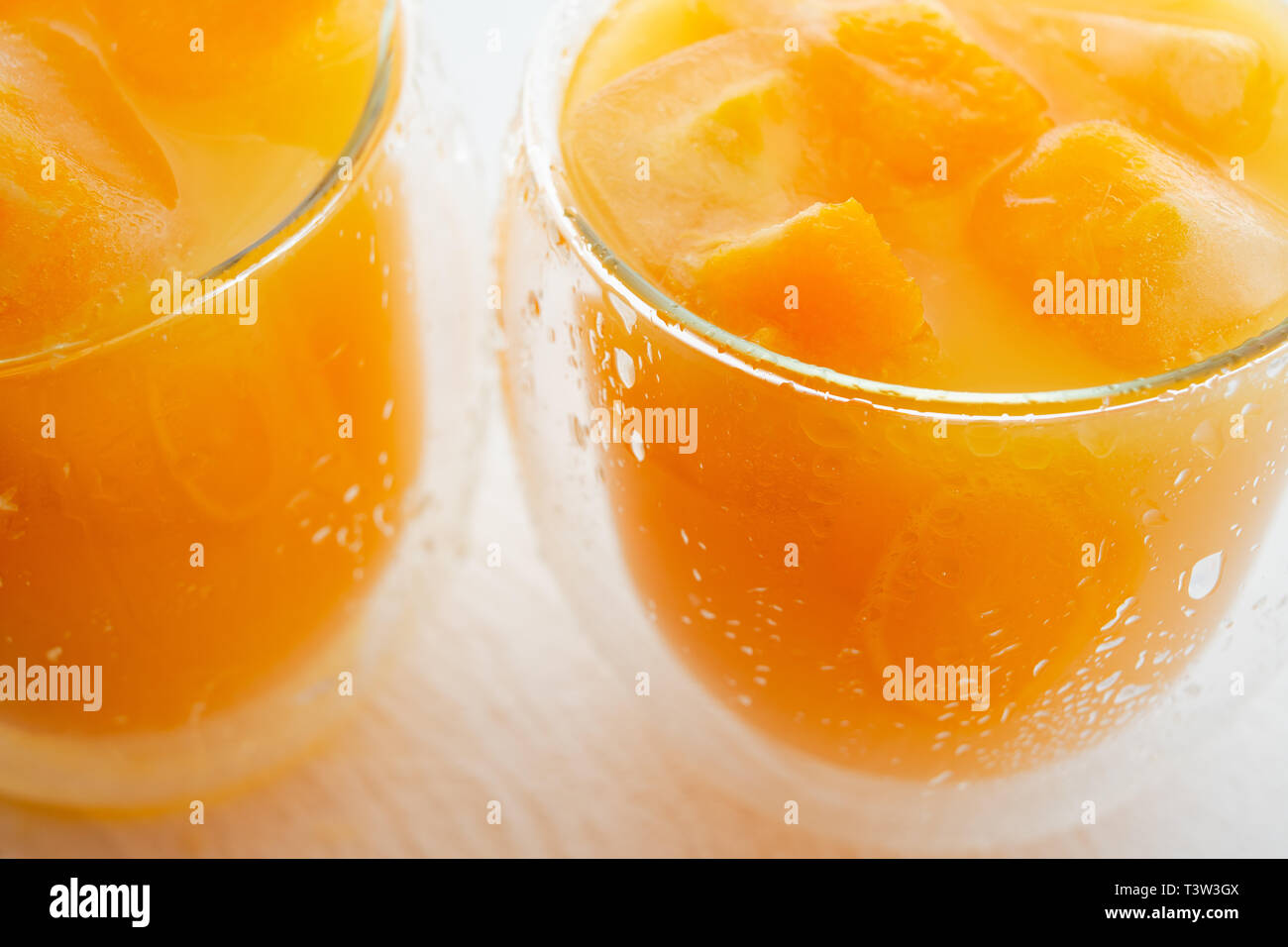 Glasses of Orange Juice with Ice Cubes, Small Pieces of Orange Fruit in Ice Cube Stock Photo