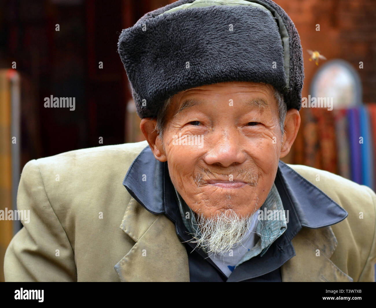 Old Chinese river fisherman wears a military-style ushanka hat and smiles for the camera. Stock Photo