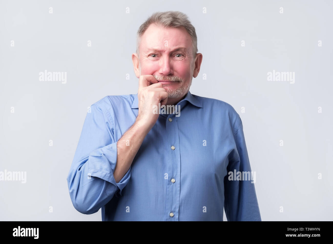 Senior man looks with a guilty apologetic expression Stock Photo