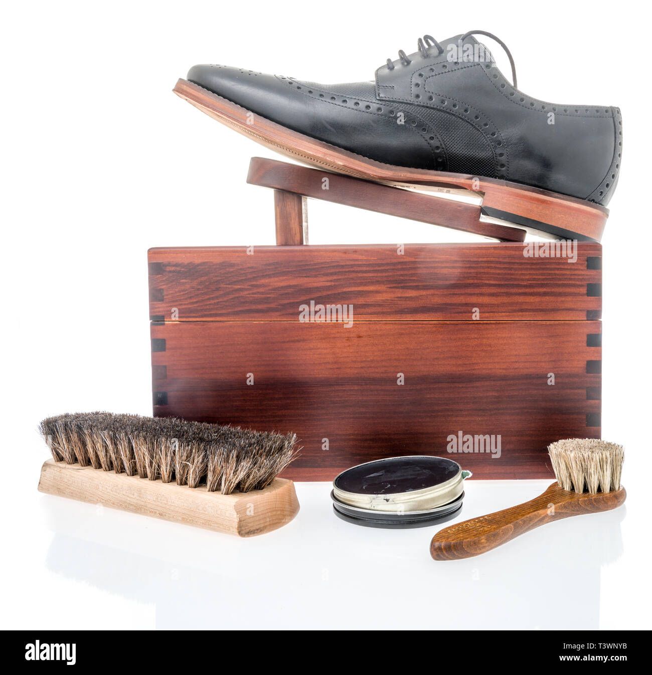 A black shoe on a shoe polish box that is ready to be shined with shoe polish, dauber and brush Stock Photo
