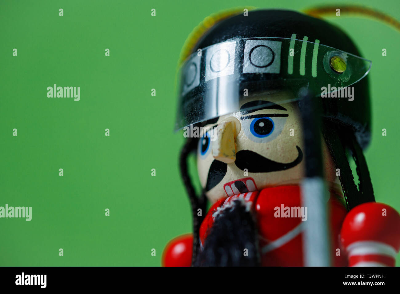 Side view of a nutcracker soldier on against a green background. Nutcracker soldier figurine in helmet. Stock Photo