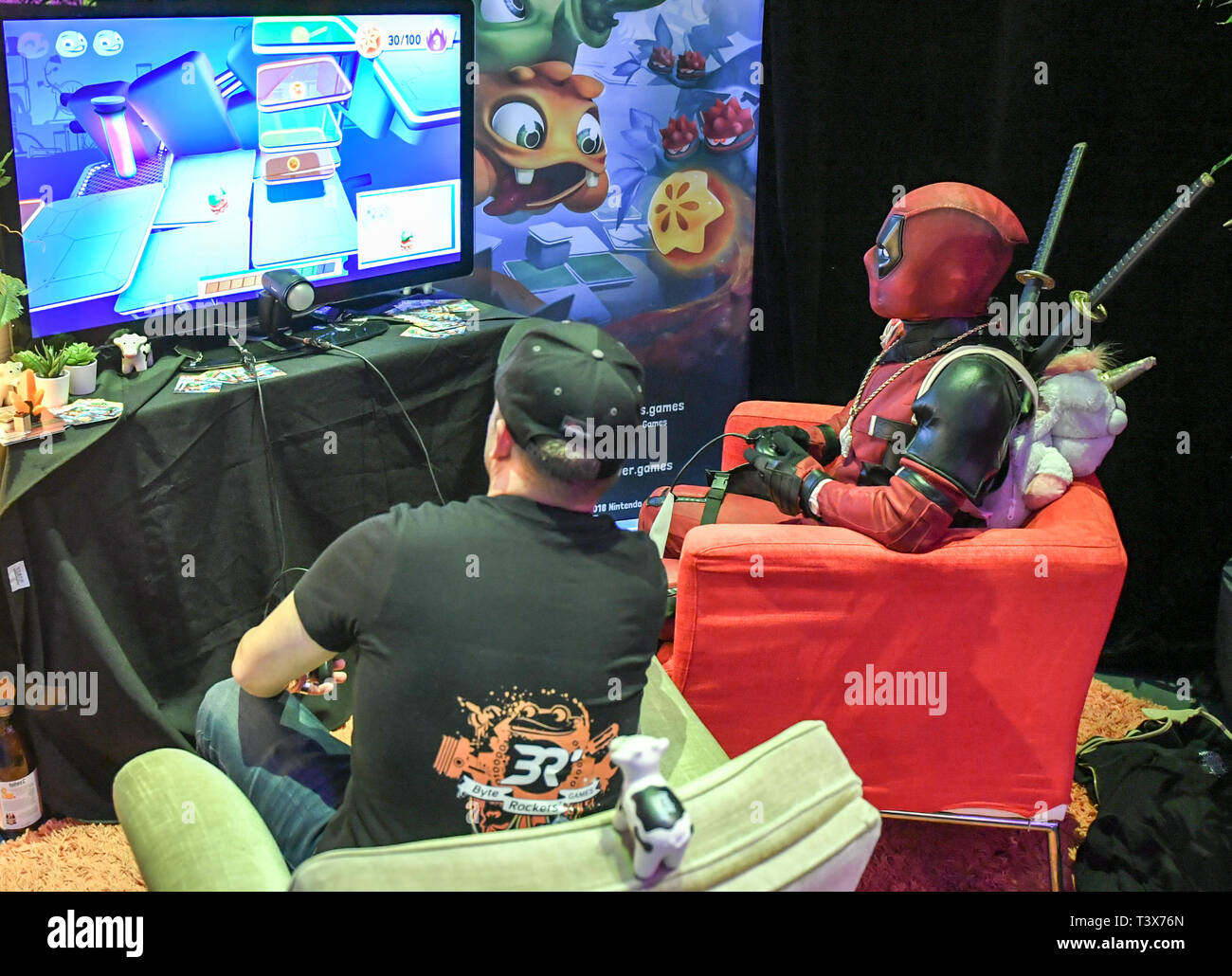Berlin, Germany. 12th Apr, 2019. A visitor dressed as a figure Deadpool  plays a computer game with a stand supervisor at the Gamefest in the  Kulturbrauerei as part of Gamesweekberlin 2019. The
