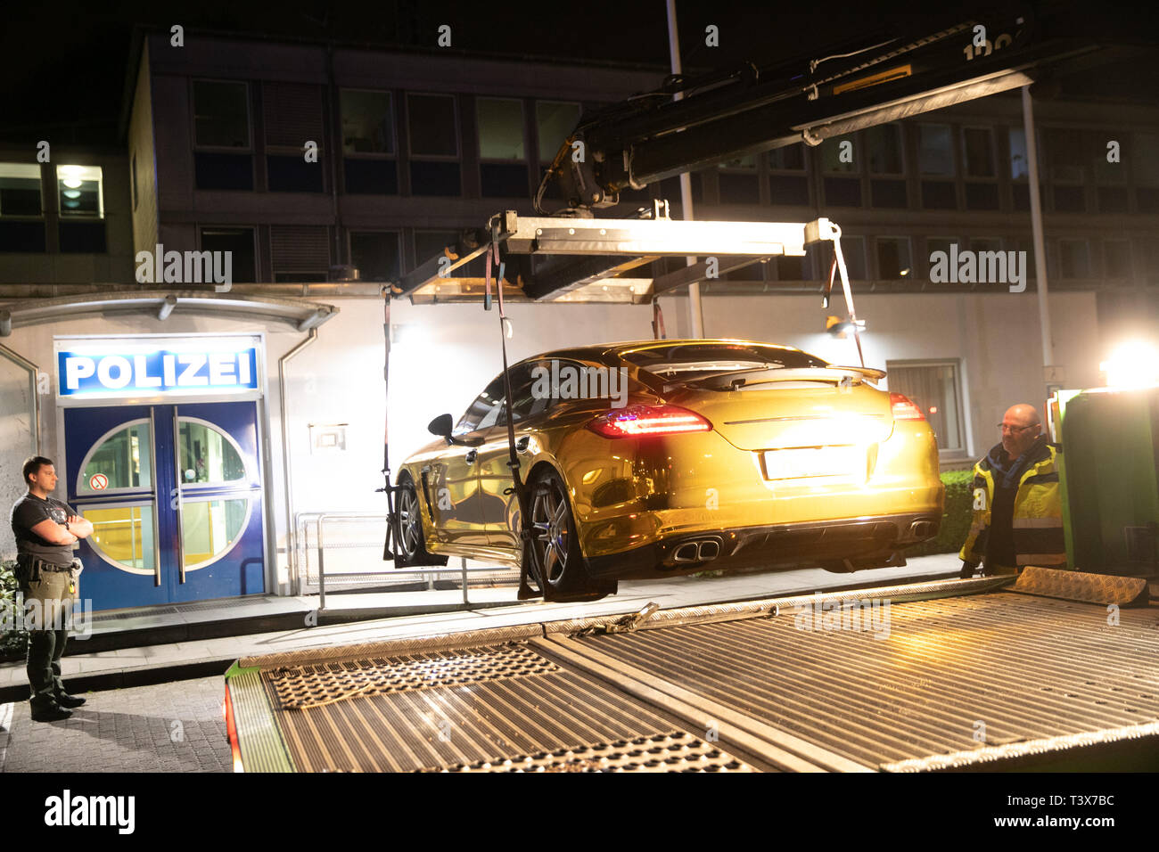 Hamburg, Germany. 03rd Apr, 2019. A policeman stands in front of a police station at a Porsche Panamera covered with gold foil, which is loaded onto a vehicle transporter. The police had taken the vehicle out of circulation because the foil strongly reflected incident light and the glare endangered other road users. Credit: Marius Roeer/dpa/Alamy Live News Stock Photo