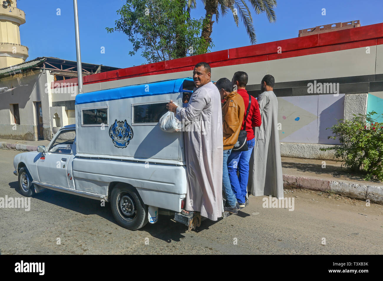 4 Arab men hitching a lift on the back of a truck at Aswan, Egypt, Africa Stock Photo