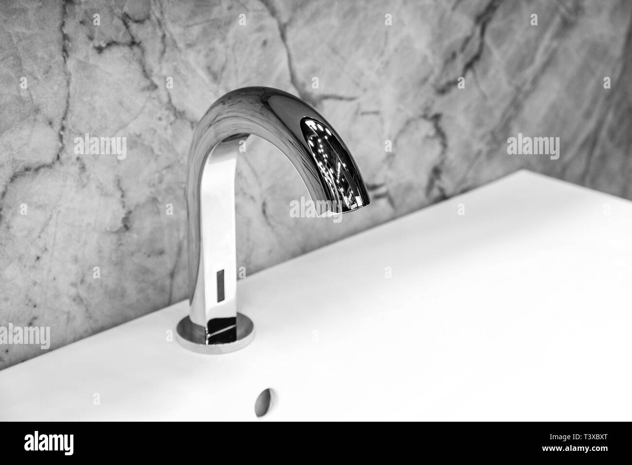 Luxury infrared faucet mixer on a white sink in a beautiful white and gray bathroom Stock Photo
