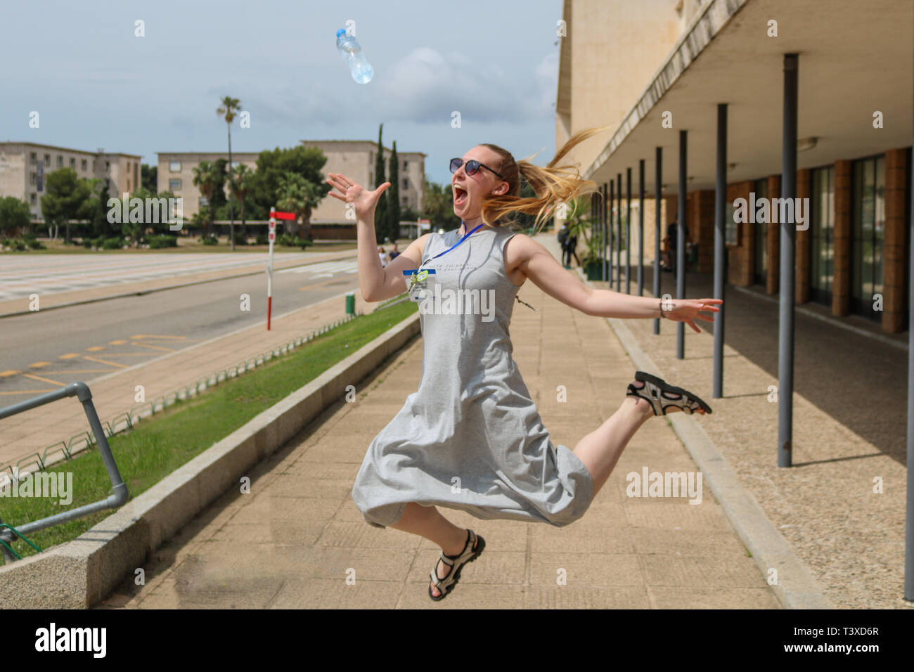 Blonde girl jumping, catching a water bottle Stock Photo