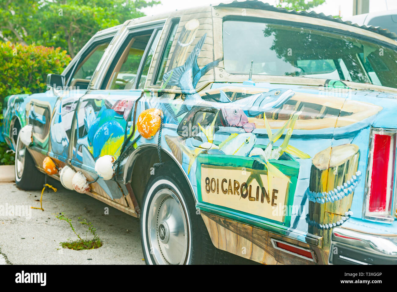 KEY WEST USA - JUNE 26 2012; Old battered car painted with wildlife and floral scene in rustic fashion parked up. Stock Photo