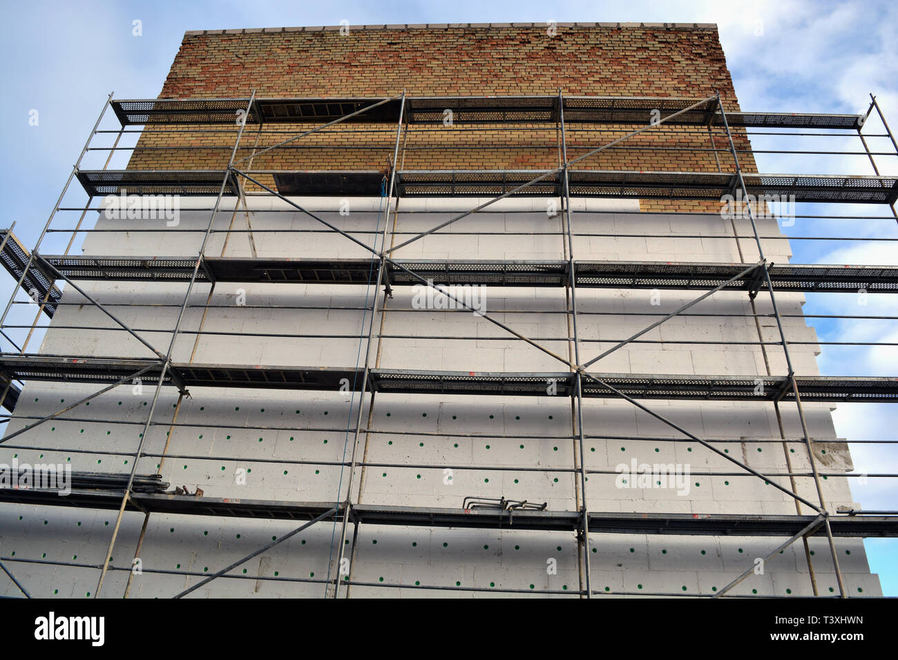 Insulating old flat house brick wall with white polystyrene and scafolding Stock Photo