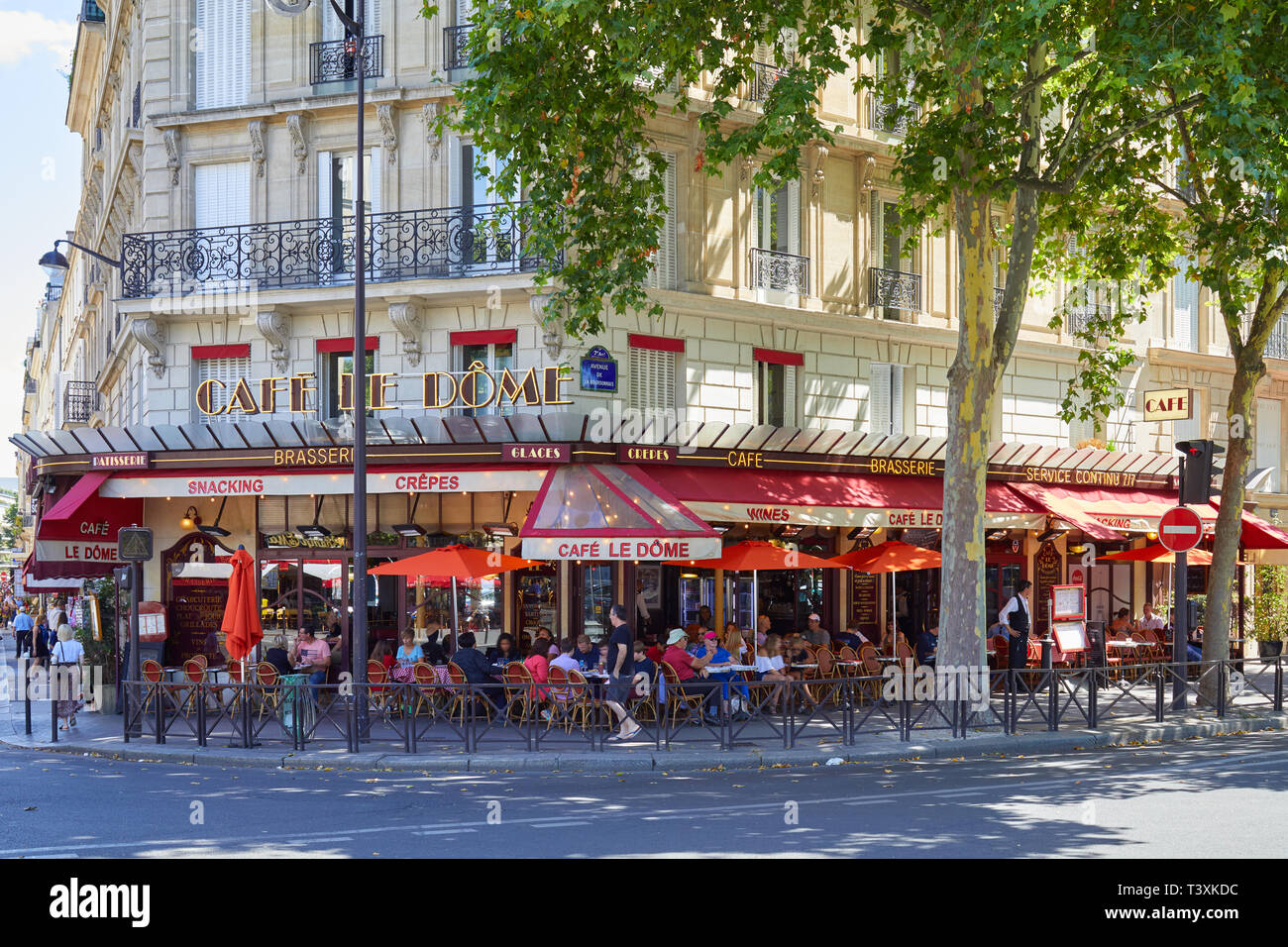 PARIS, FRANCE - JULY 21, 2017: Typical cafe brasserie with sidewalk tables with people and tourists sitting in a sunny summer day in Paris, France Stock Photo