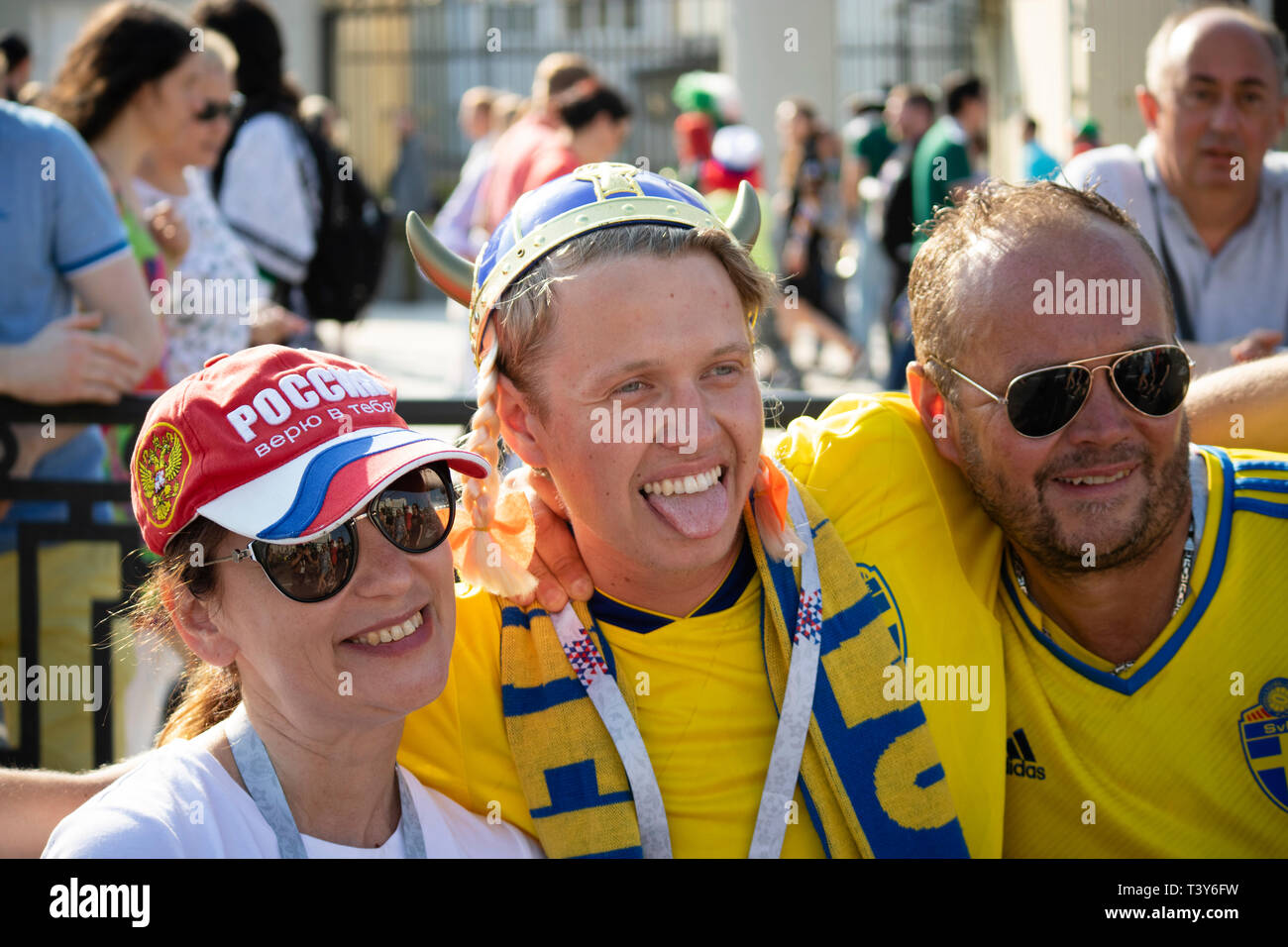 Beautiful smiling female Russian fan poses for camera with two male Swedish fans - FIFA World Cup Russia 2018 Mexico v Sweden, Ekaterinburg Stock Photo