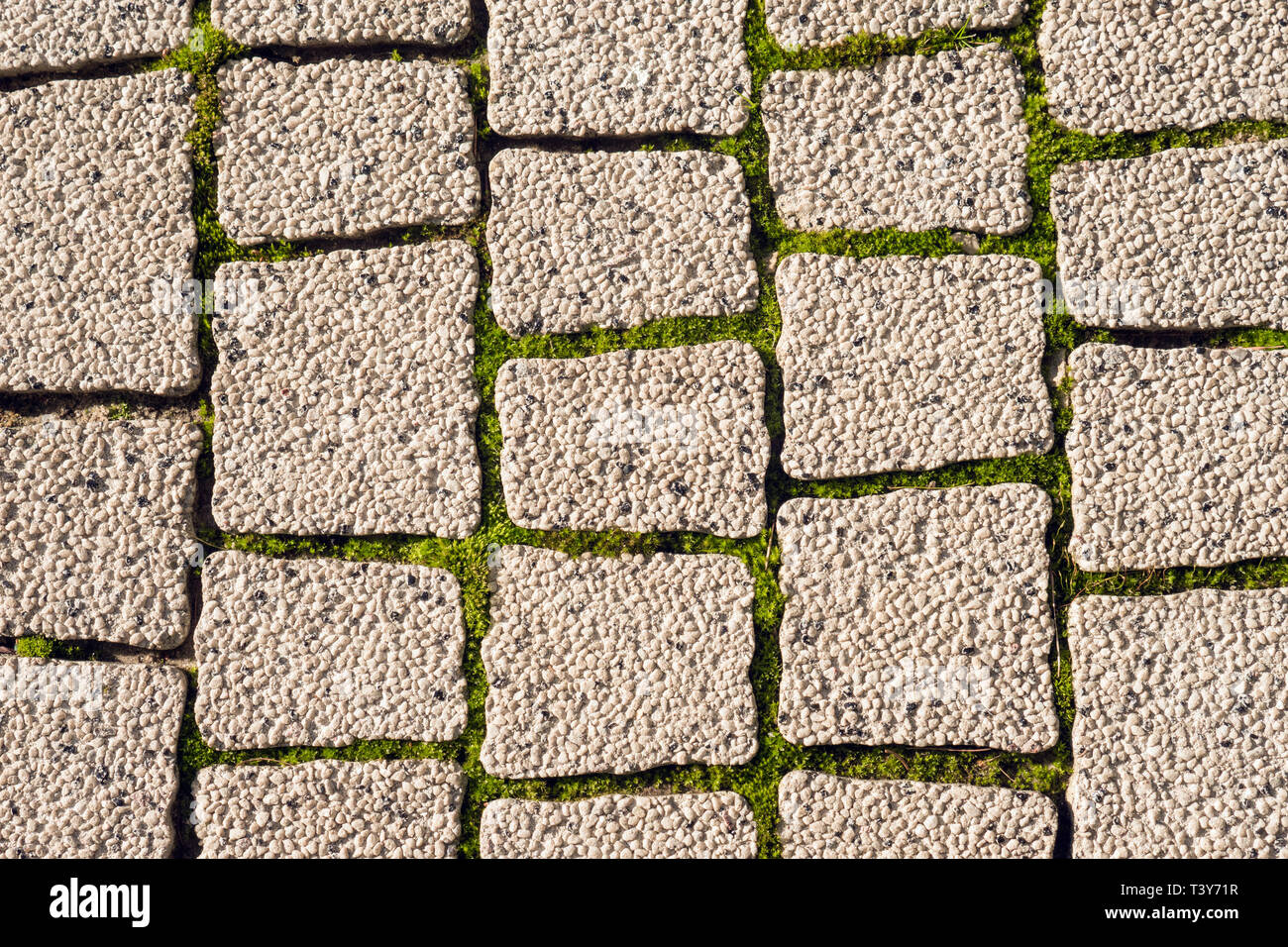 cobblestone street surface with weeds growing in joints Stock Photo