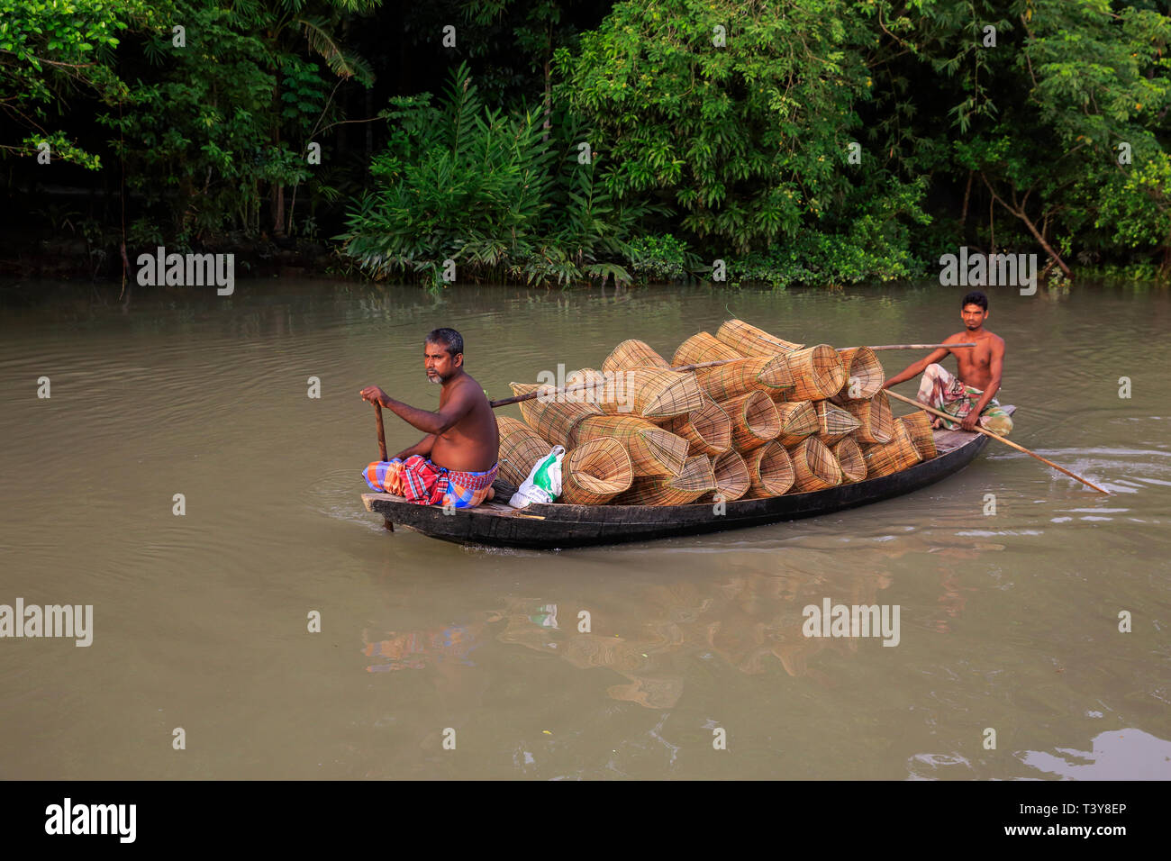 Traders rowing a boat full of fishing traps on the way to the Boitghata floating market at Najirpur in Pirojpur, Bangladesh. Stock Photo