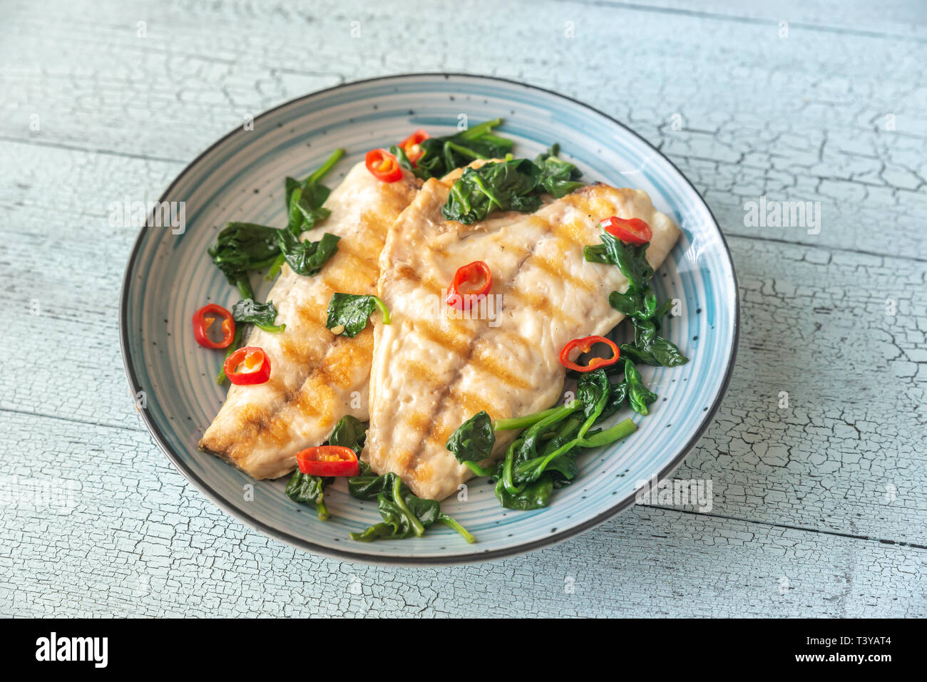 Grilled sea bream fish fillet with spinach and chili pepper Stock Photo