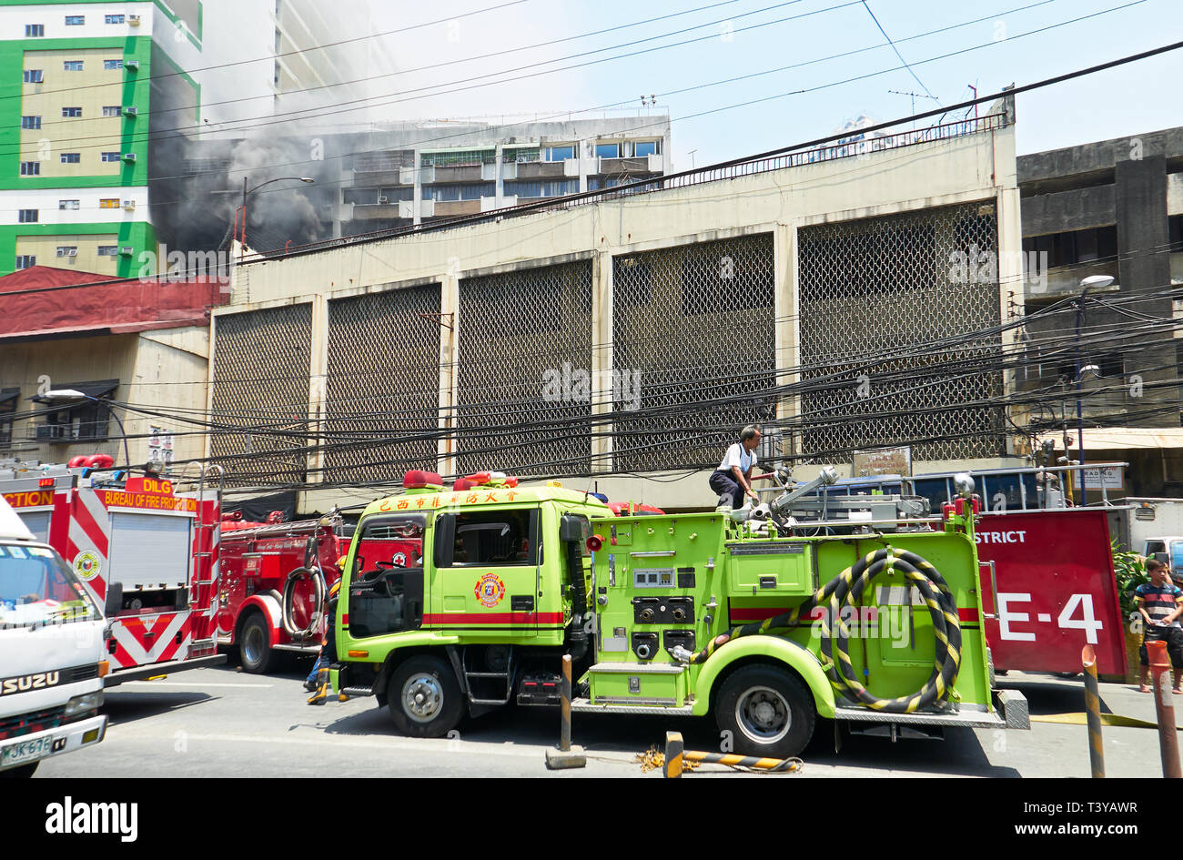 Manila, Philippines: Several fire cars with firemen at work, trying to extinguish a fire in an apartment building in Binondo Stock Photo