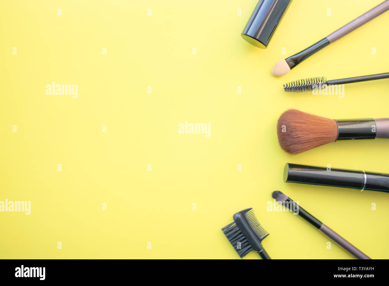Makeup brushes, brushes for everyday makeup. Cosmetic items on yellow background, closeup. With empty space from the left. Stock Photo