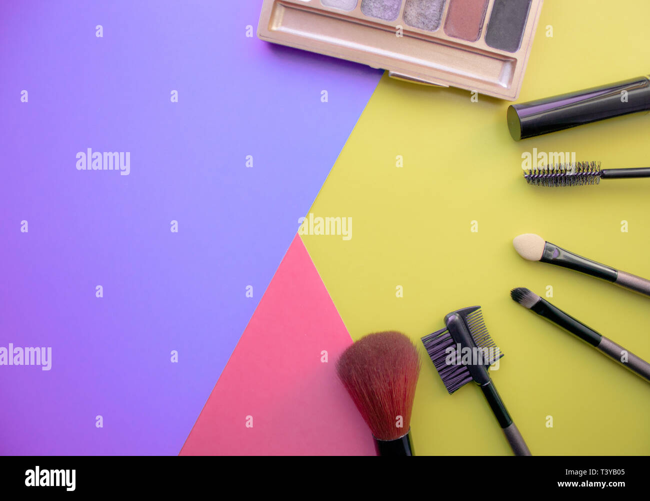 Makeup and makeup brushes, eye shadows on a colored background. Cosmetics for the face. With empty space on the left. View from above Stock Photo