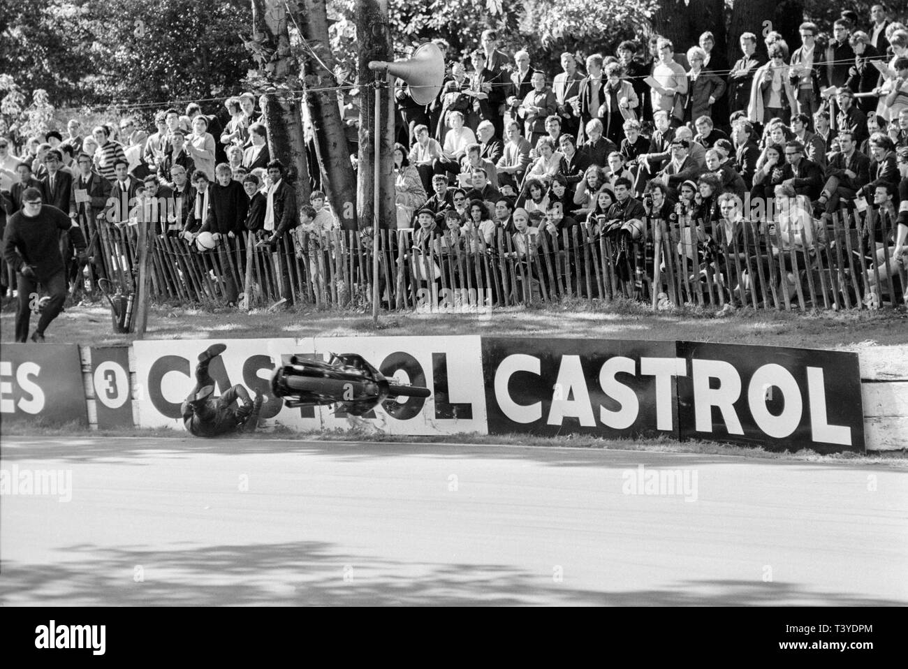 Motorcycle racing at Crystal Palace near London in 1968. A motorcycle racer crashes and falls in to the circuit wall whilst approaching in to a bend on the track. The Crystal Palace racing circuit was closed in 1972. Stock Photo