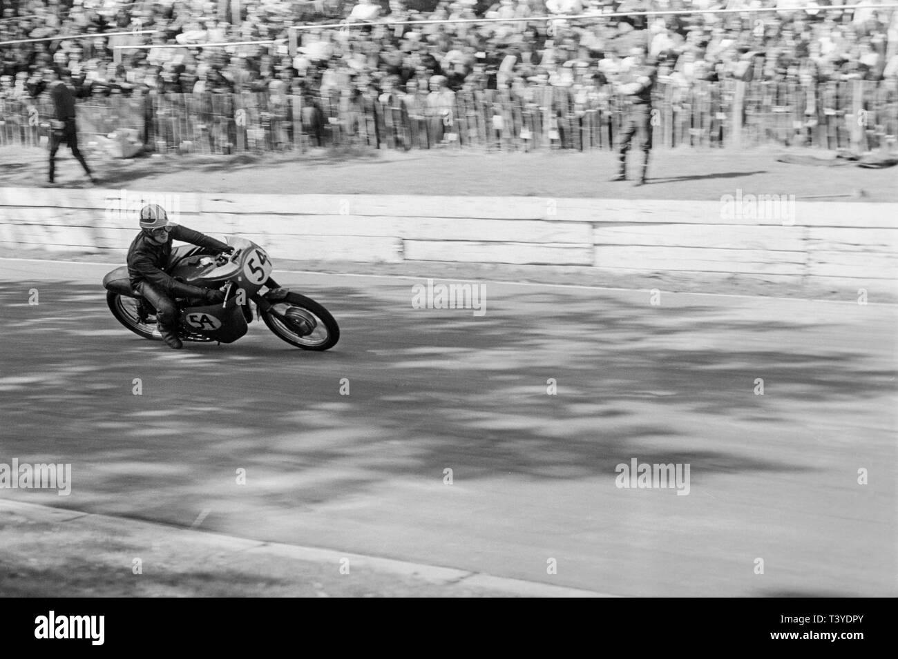 Motorcycle racing at Crystal Palace near London in 1968. A motorcycle racer, number 54, approaching in to a bend on the track. The Crystal Palace racing circuit was closed in 1972. Stock Photo
