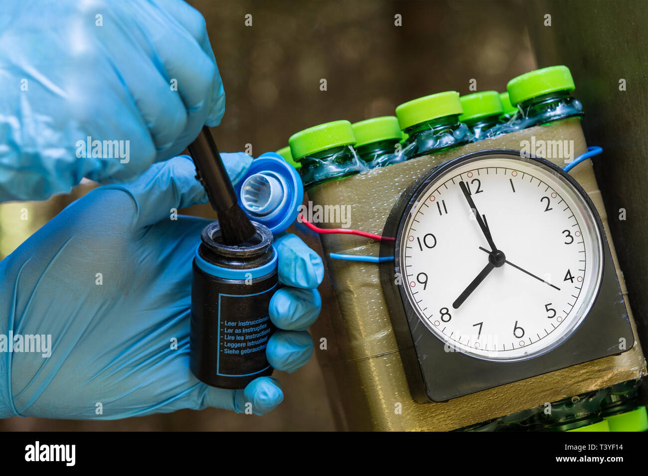 Time bomb. Forensic expert. Fingerprints search. Dummy weapon. Police detective investigates clues. Human hands, blue gloves, brush. Terrorism, crime. Stock Photo