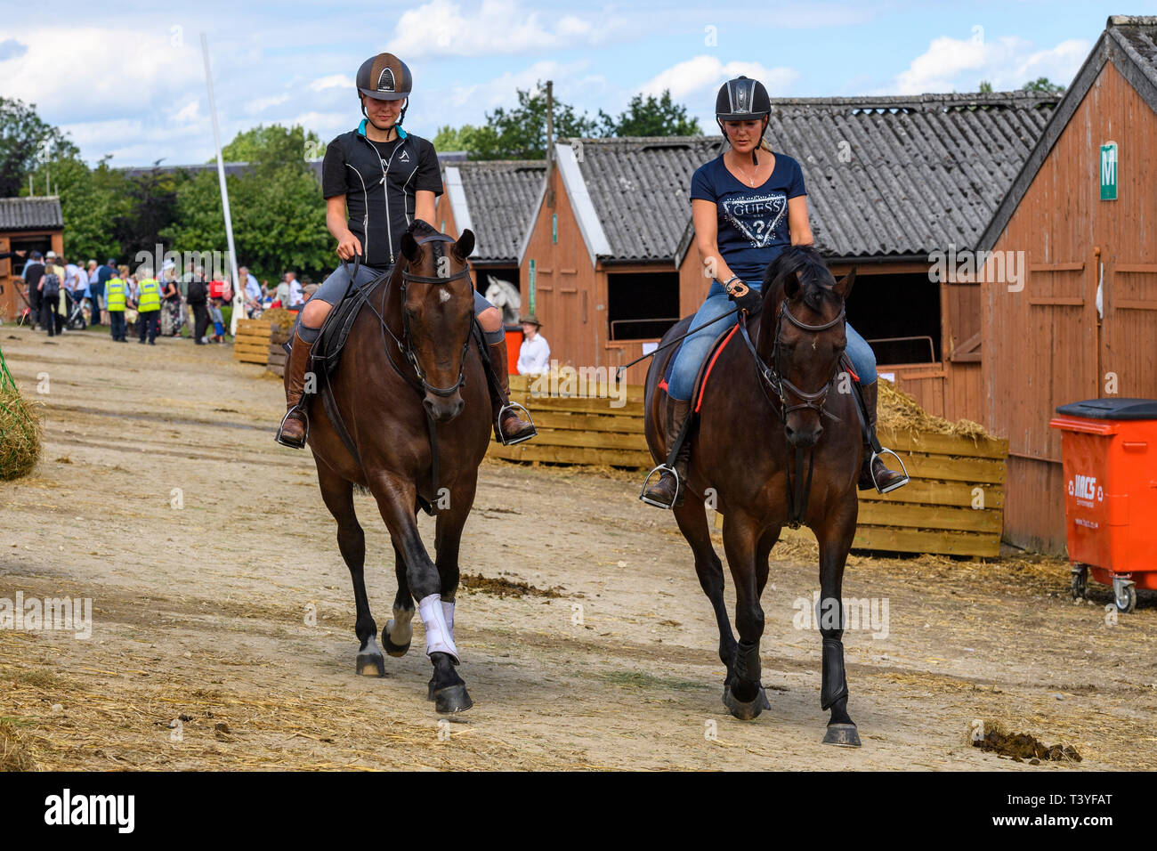 Female entrants in equine class wearing riding hats, ride horses in