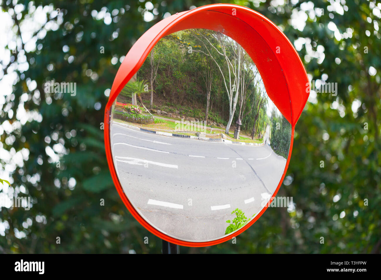 Round mirror in red frame on metal pole at crossing streets for safety Stock Photo