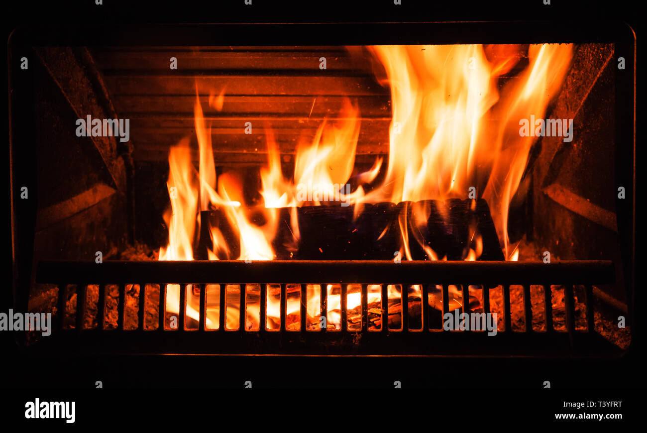 Firewood burns in the fireplace at night, close up background photo Stock Photo