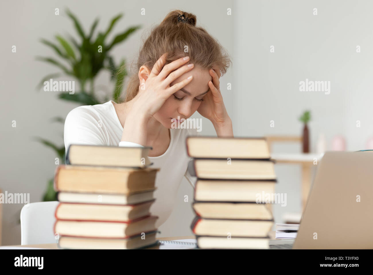 Upset woman sitting with closed eyes, annoyed by learning Stock Photo