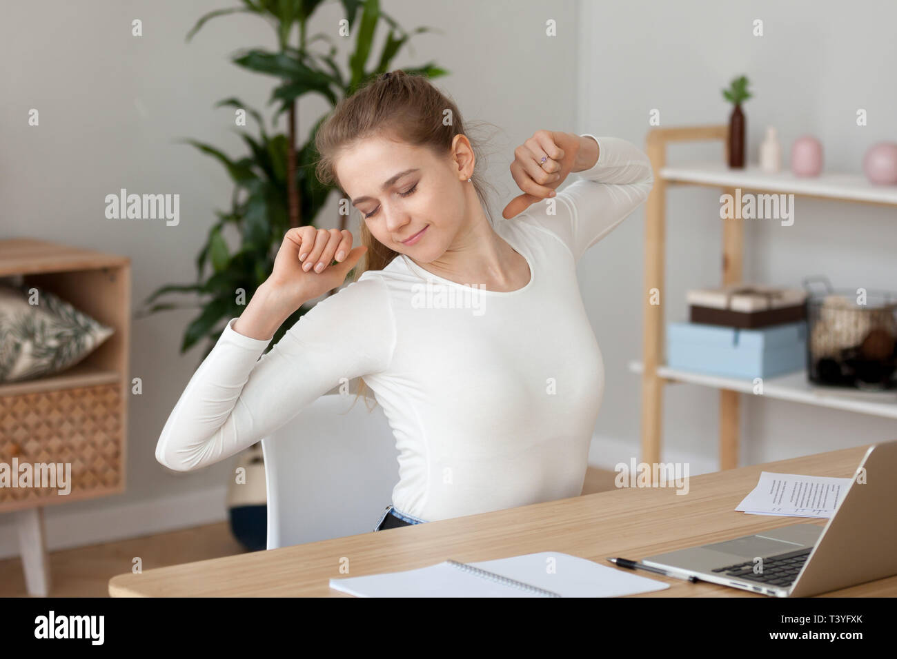 Satisfied young woman stretching, doing exercise at workplace Stock Photo