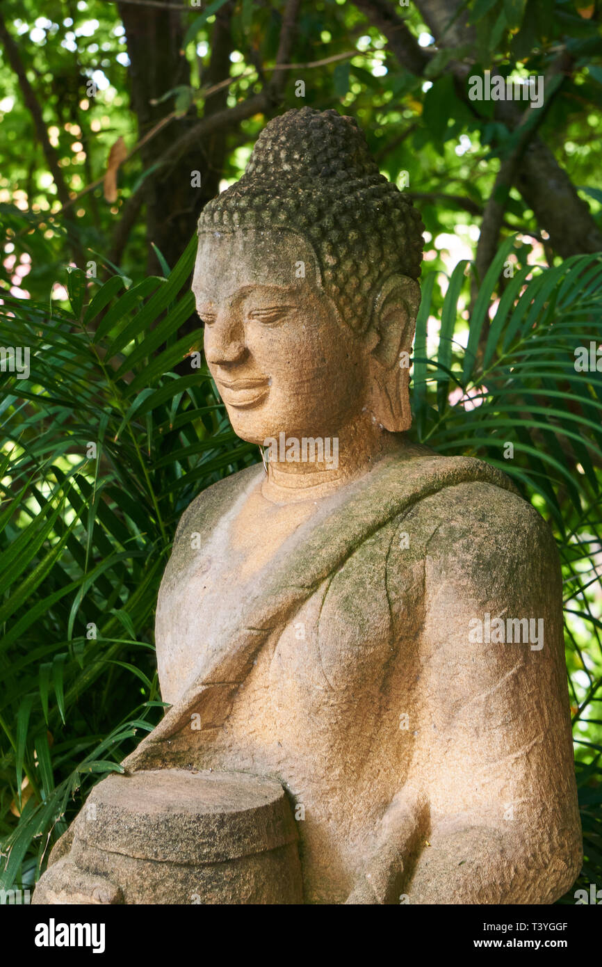 Buddhist statue of Buddha surrounded by tropical plants inside the