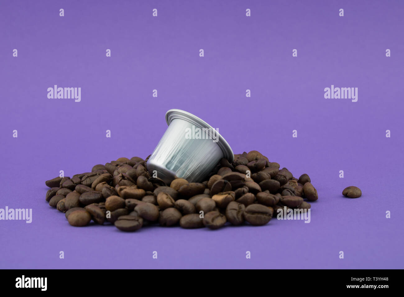 Espresso coffee capsule or coffee pod on coffee beans, purple