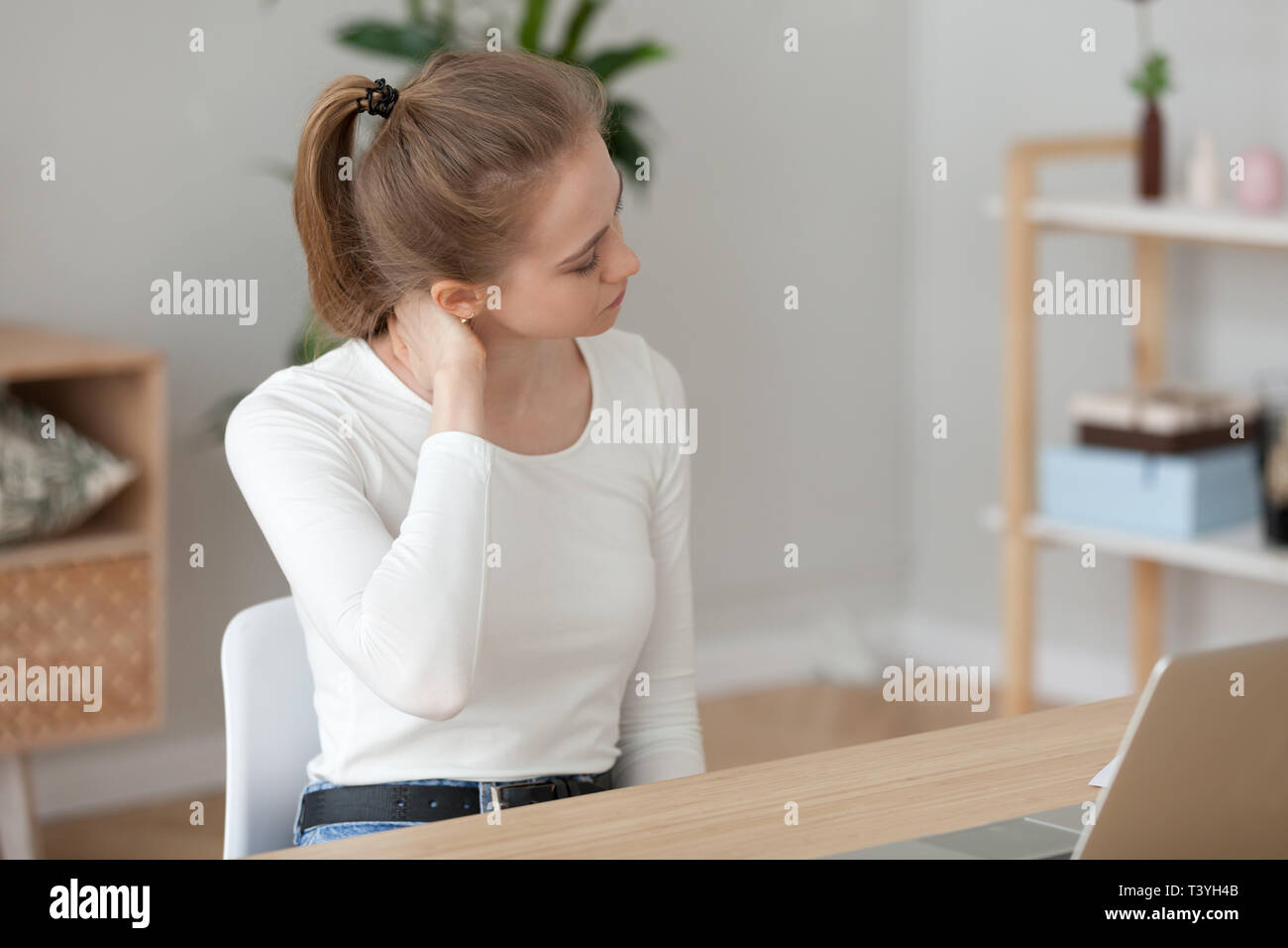 Tired woman feeling pain after sedentary computer work, massaging neck Stock Photo