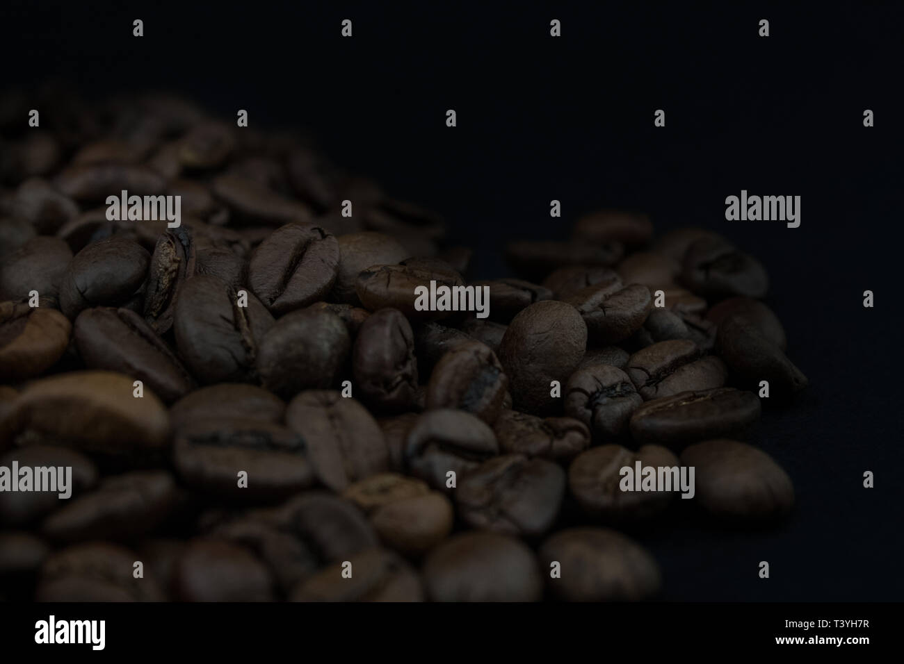 Roasted coffee beans on black background Stock Photo - Alamy