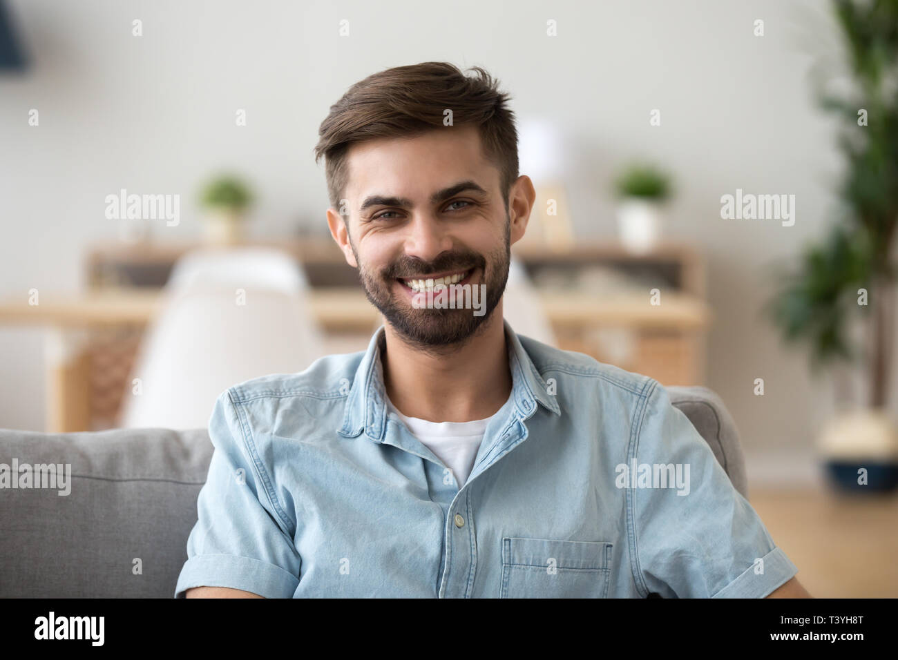 Head shot portrait of happy smiling man sitting on sofa at home Stock Photo