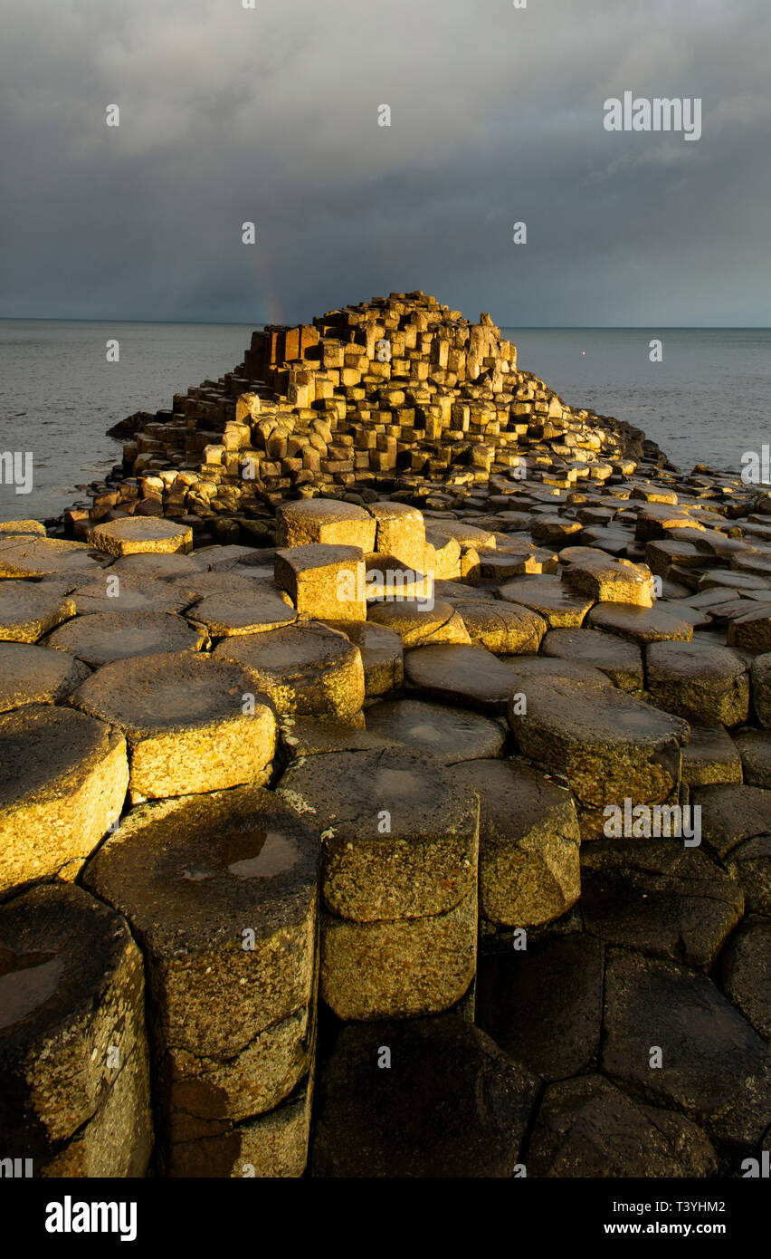 Northern Ireland, Country Antrim, Giant's Causeway. Rainbow behind the hexagonal basalt rock formations of the Wishing Chair, part of the Giant's Caus Stock Photo