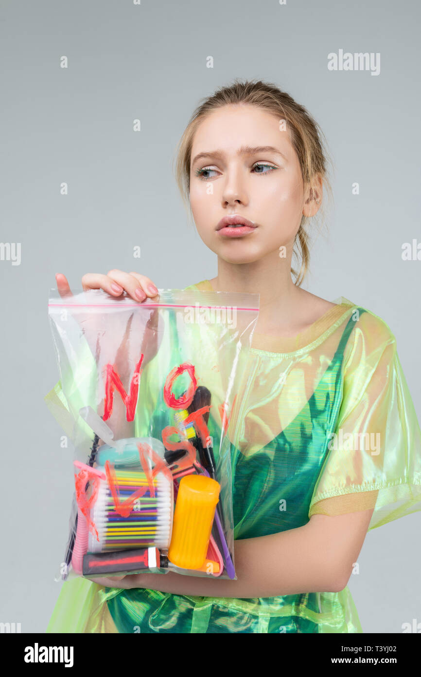 Cosmetics items. Appealing young model with natural makeup holding