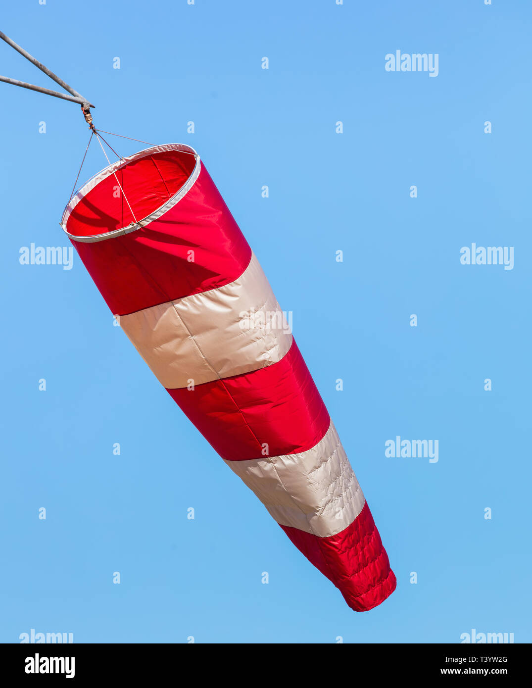 A windsock in an airport against blue sky. A windsock is a conical