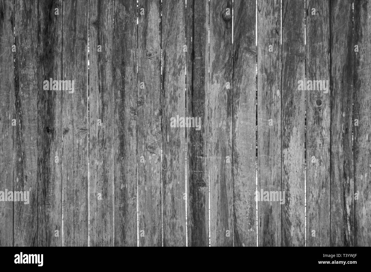Full frame background of an old, faded and scratched wooden board wall or fence in black and white. Stock Photo