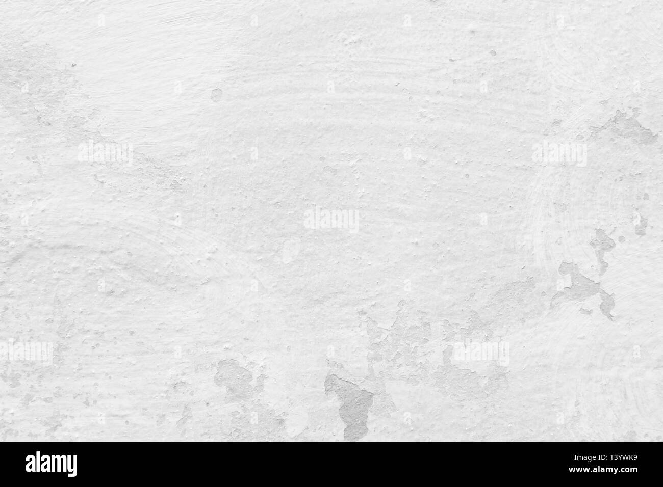 Close-up of a stone or concrete wall painted in white, paint slightly peeled off. Full frame texture background in black and white. Stock Photo