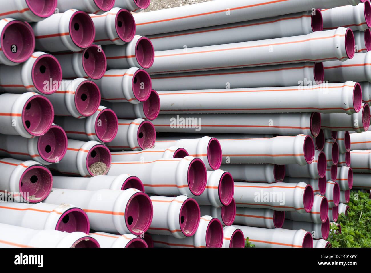 many stacked long plastic pipe tubes ready for building a water supply and irrigation system on agricultural grounds Stock Photo