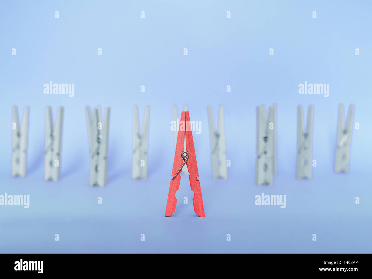 Unique, individuality, outstanding,leadership and think different concept. Red wooden clip stand out of colorless clips on blue backgrounds Stock Photo