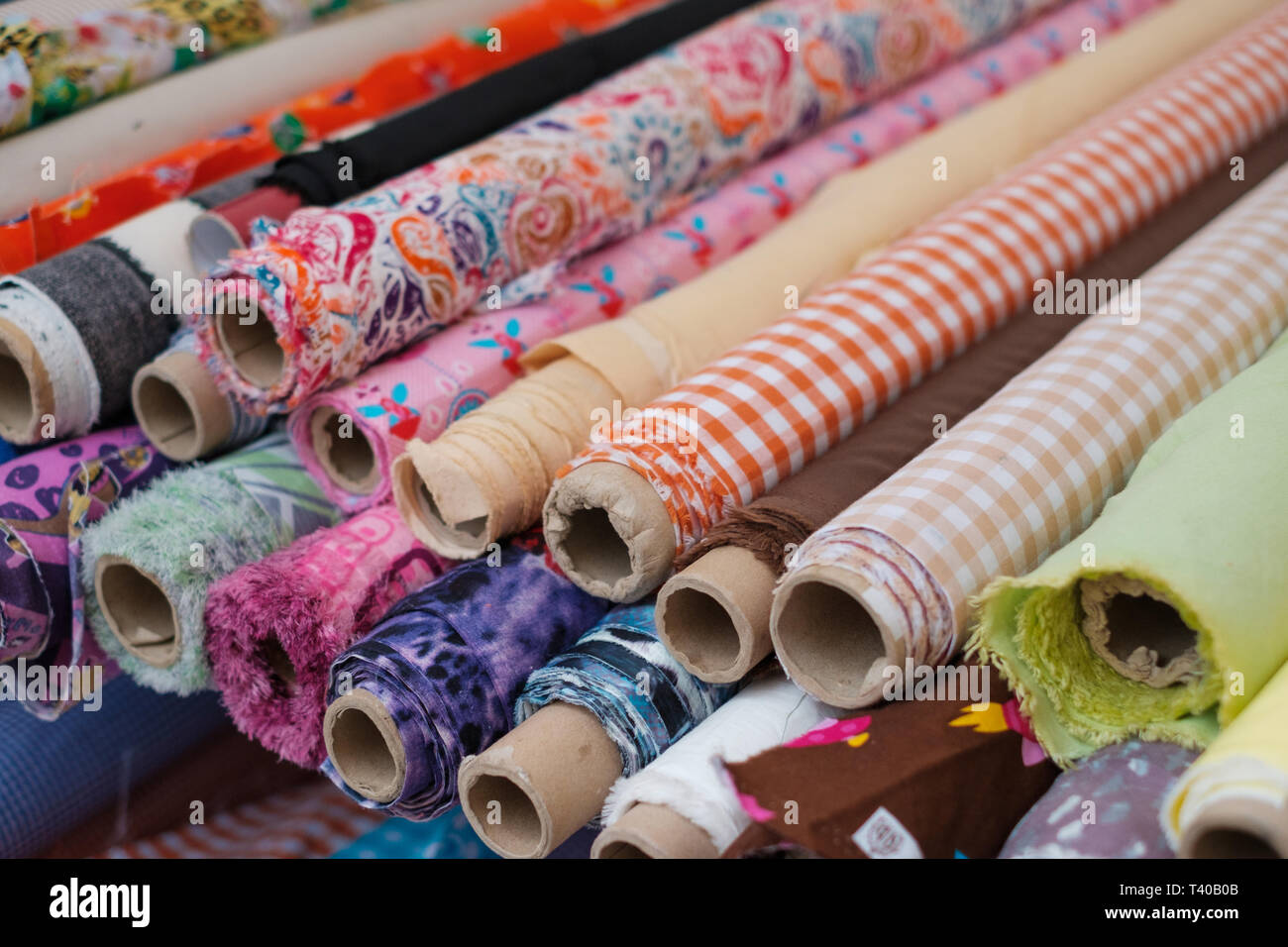 many fabric rolls and colorful textiles at market - Stock Photo